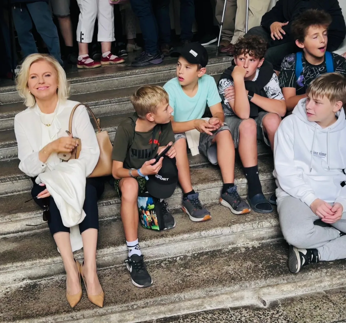 Monika Nebeská sedí na schodech mezi školáky